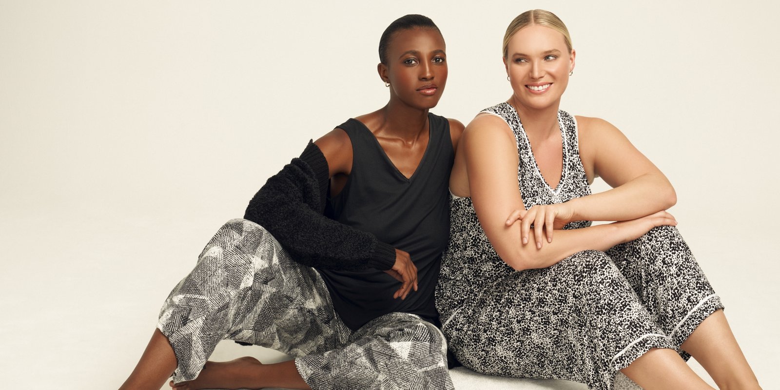Two Anne Klein models in sleepwear sets sitting down