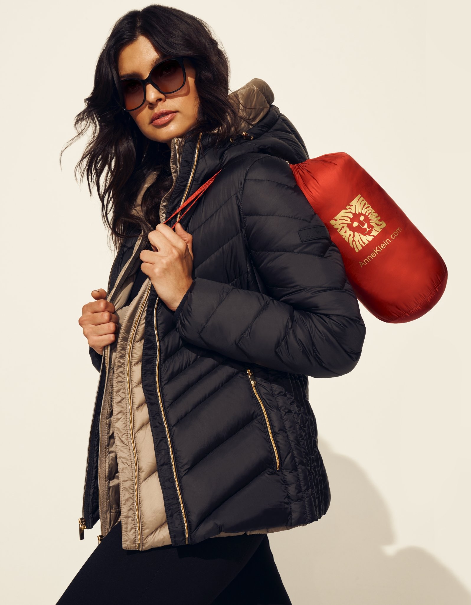 Anne Klein model wearing 2 puffer jackets carrying a third packed jacket