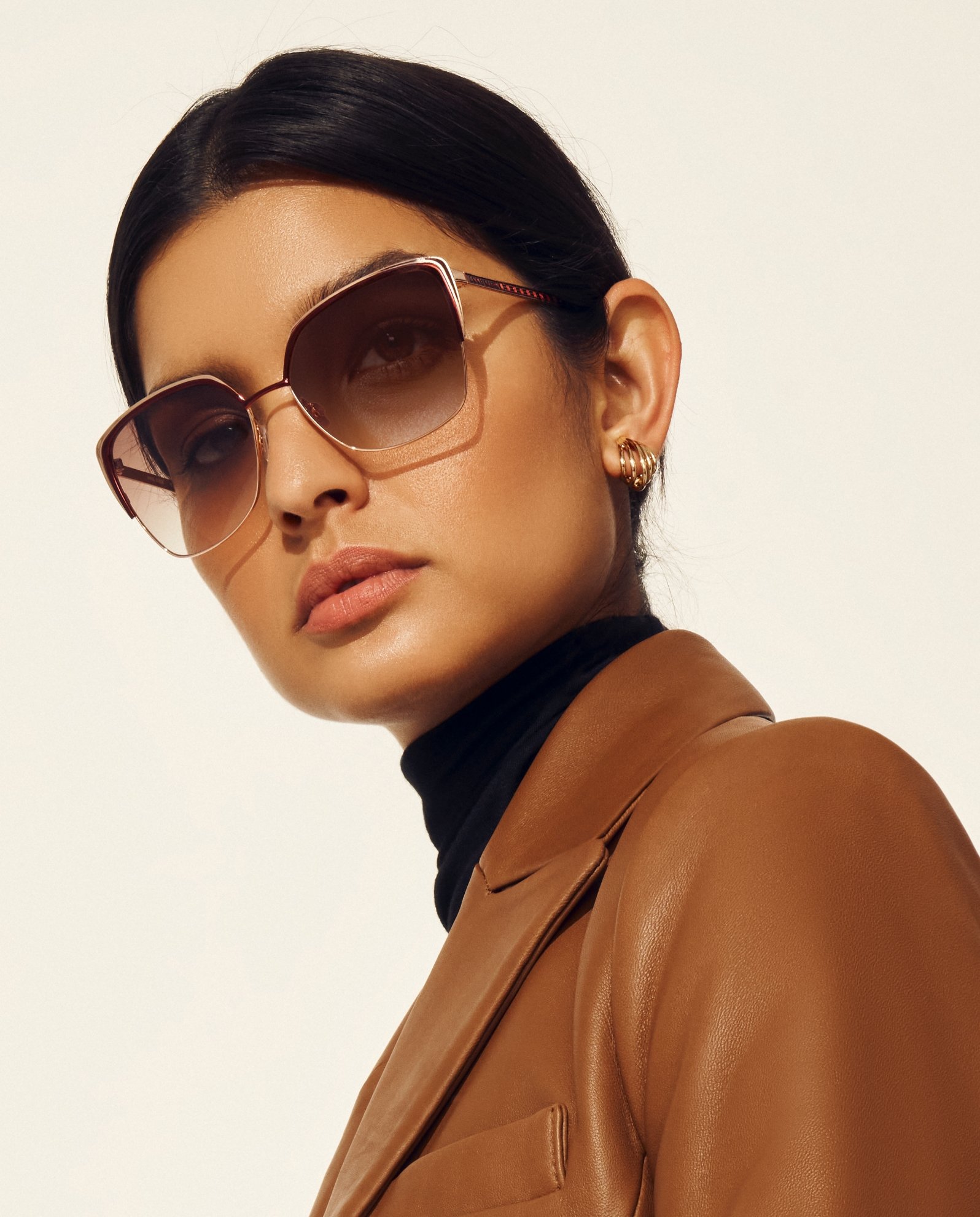 Anne Klein model in brown leather jacket and oversized sunglasses